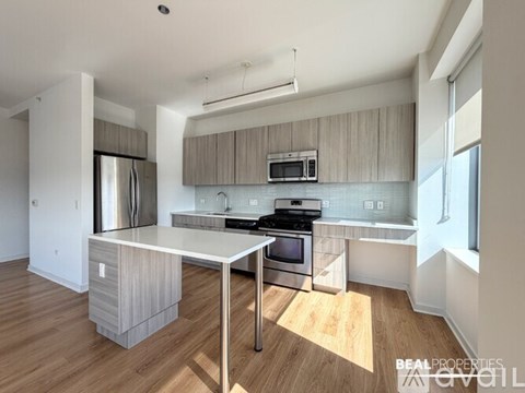 A modern kitchen with wooden floors and stainless steel appliances.