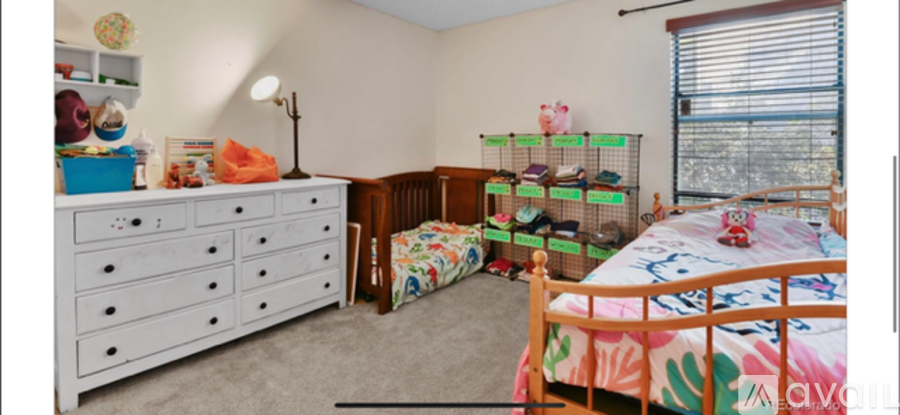A bedroom with a white dresser and a bed with a colorful comforter.