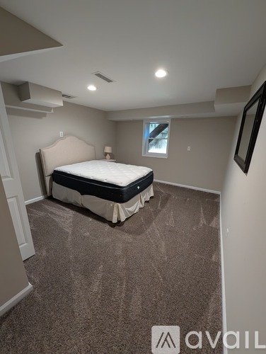 A bedroom with a bed, carpet, and a window.