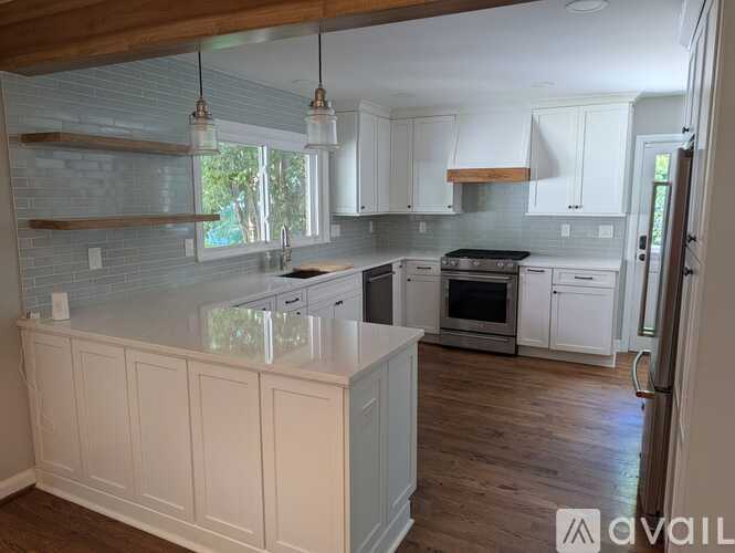 A kitchen with white cabinets and a wooden floor.