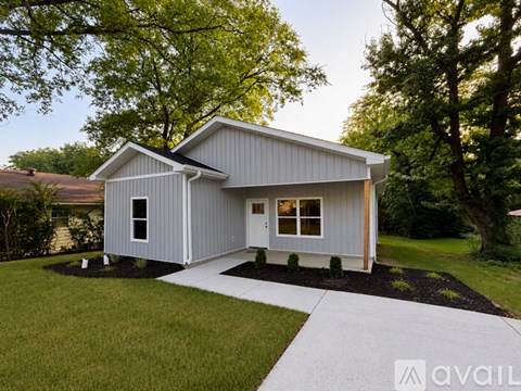 A modern house with a grey exterior and a white walkway leading to the front door.