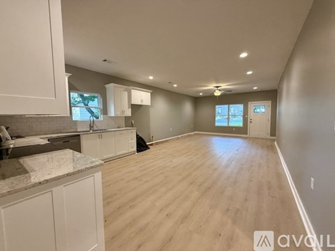 A spacious kitchen with white cabinets and a marble countertop.