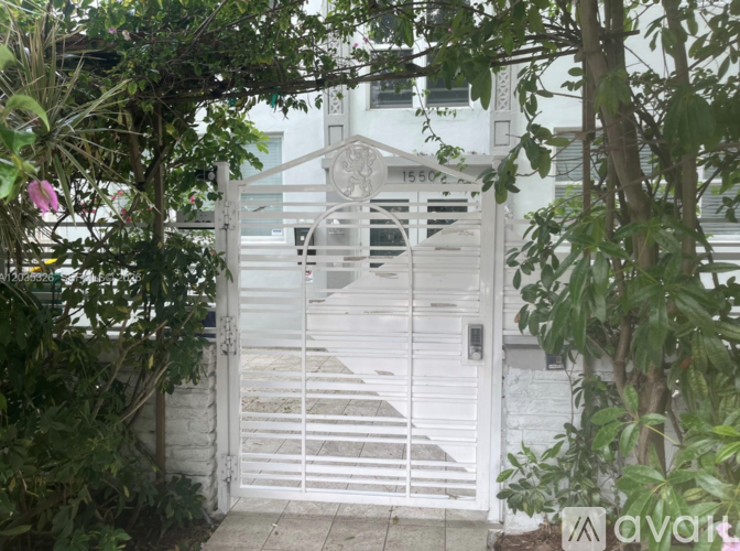 A white gate with a number 1550 on it is surrounded by greenery.