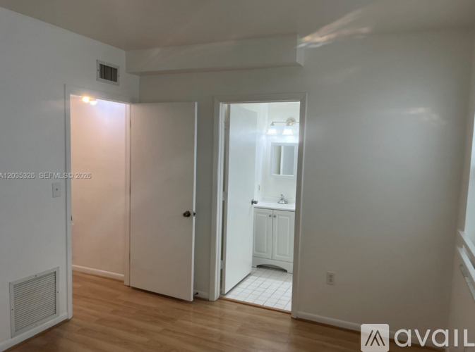 A room with a white door and a white cabinet with a mirror above it.