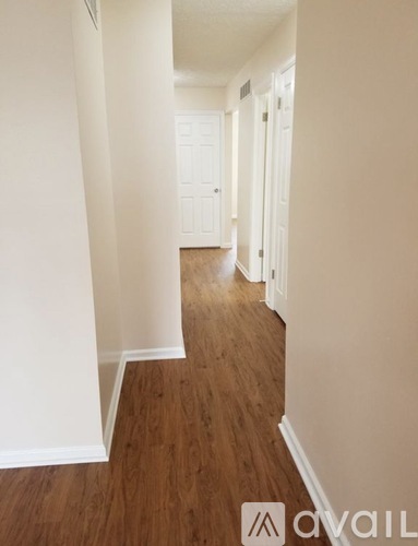 A hallway with wood floors and white walls.