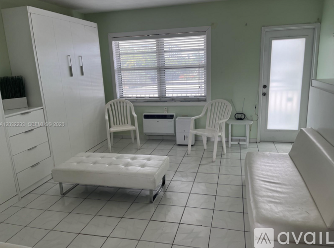 A white chair and ottoman are in a room with a window.