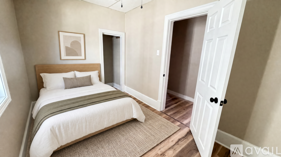 A bedroom with a bed, a rug, and a door.