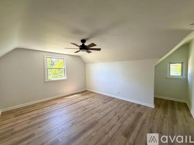 A room with a ceiling fan and two windows.