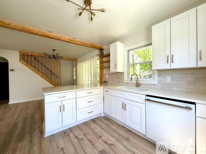 A kitchen with white cabinets and a wooden staircase.