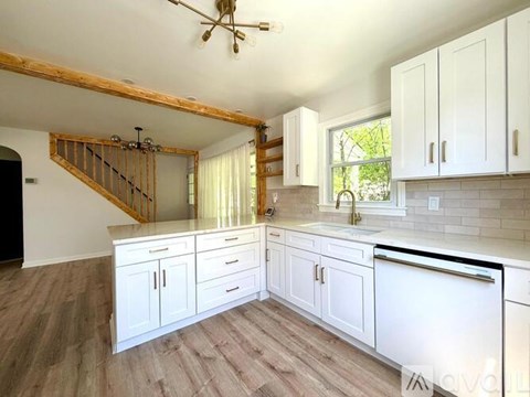 A kitchen with white cabinets and a wooden staircase.