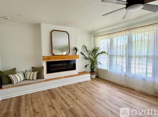 A living room with a fireplace, a mirror, and a potted plant.