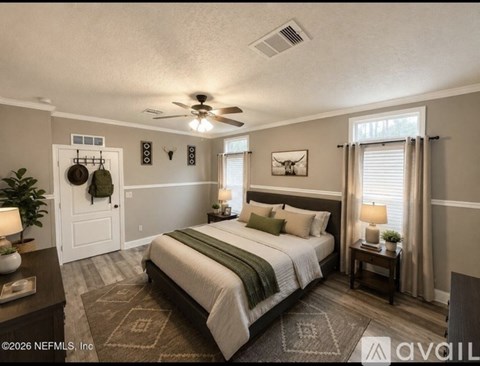 A bedroom with a large bed, a ceiling fan, and a rug on the floor.