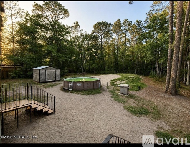 A backyard with a pool surrounded by trees.