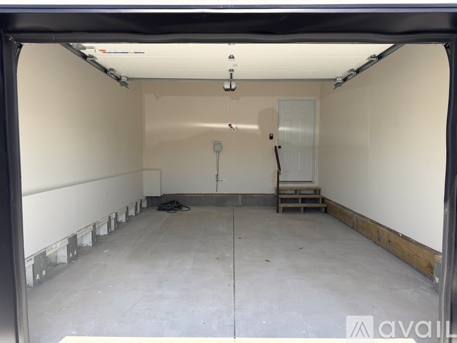 A spacious, empty room with a concrete floor and walls, and a door on the right side.