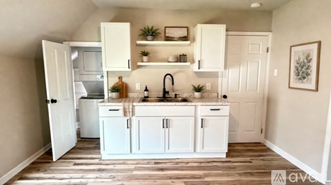 A kitchen with white cabinets and a wooden floor.