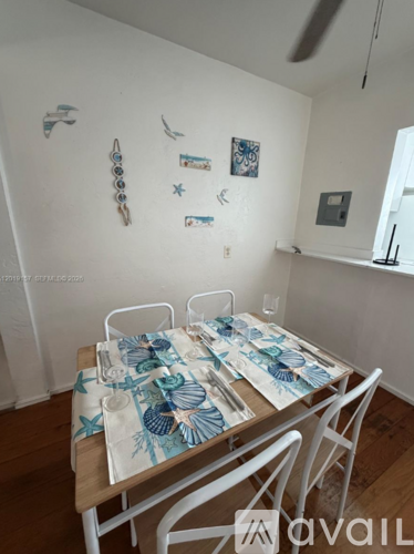 A dining table with a blue and white tablecloth and chairs.