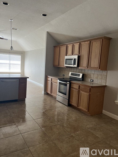 A kitchen with brown cabinets and a white microwave.