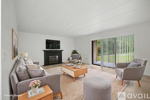 A living room with a grey couch, a grey armchair, a coffee table, a fireplace, and a painting on the wall.