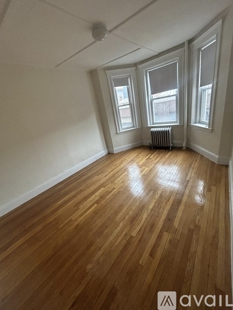 A room with wooden floors and three windows.