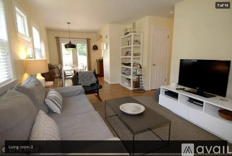 A living room with a grey couch and a television on a white stand.
