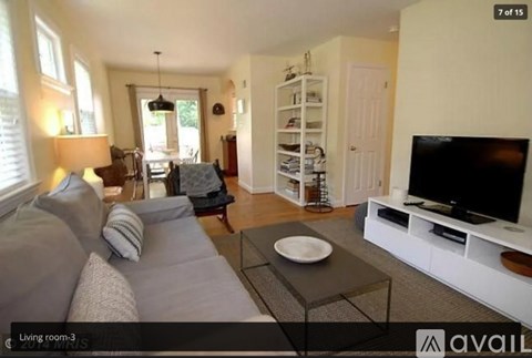 A living room with a grey couch and a television on a white stand.