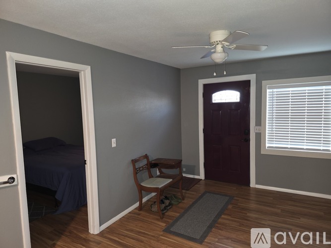 A room with a bed, chair, and ceiling fan.