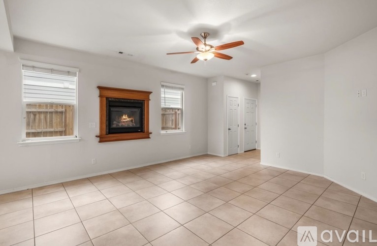 A spacious room with a fireplace and a ceiling fan.