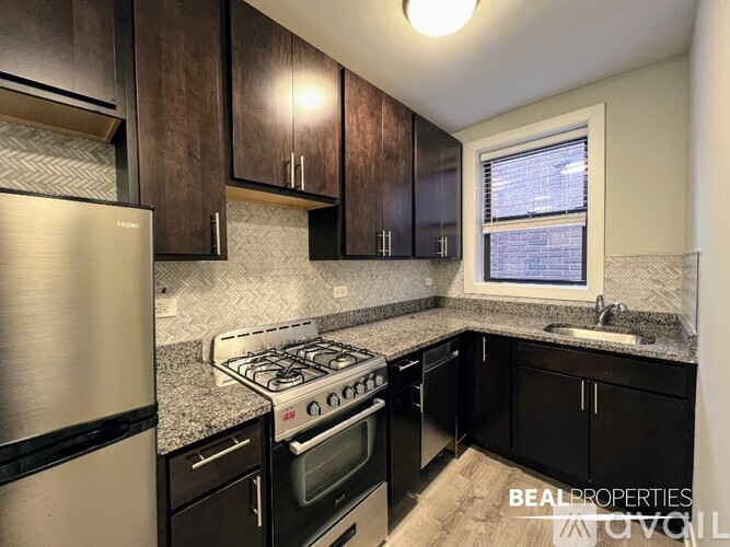 A kitchen with black cabinets and a stainless steel refrigerator.
