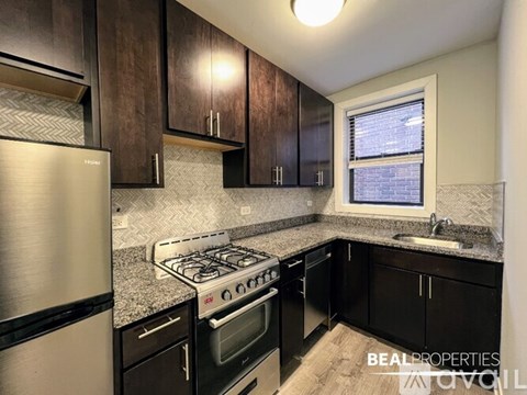 A kitchen with black cabinets and a stainless steel refrigerator.