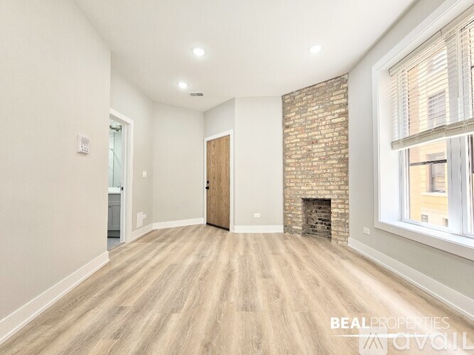 A spacious room with a brick fireplace and wooden flooring.