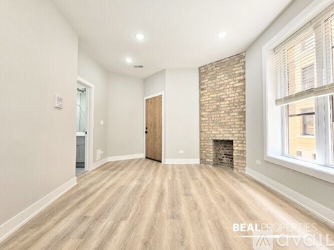 A spacious room with a brick fireplace and wooden flooring.