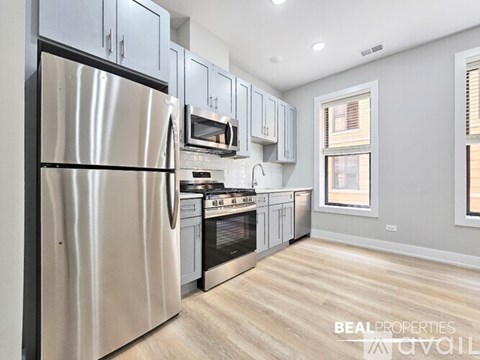 A modern kitchen with a stainless steel refrigerator and wooden flooring.