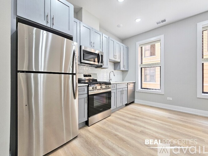 A modern kitchen with a stainless steel refrigerator and wooden flooring.