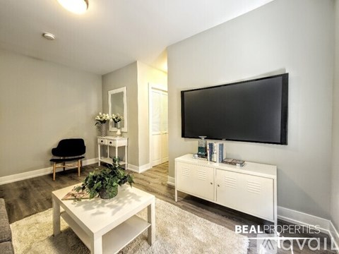 A living room with a white coffee table and a black flat screen TV mounted on the wall.