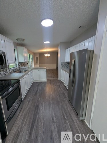 A kitchen with white cabinets and a grey floor.