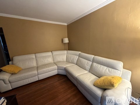 A white leather sectional sofa with a yellow pillow on it.