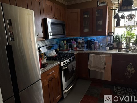 A kitchen with a stainless steel refrigerator and wooden cabinets.