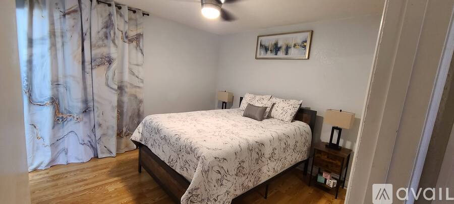 A bedroom with a bed, nightstands, and a painting on the wall.
