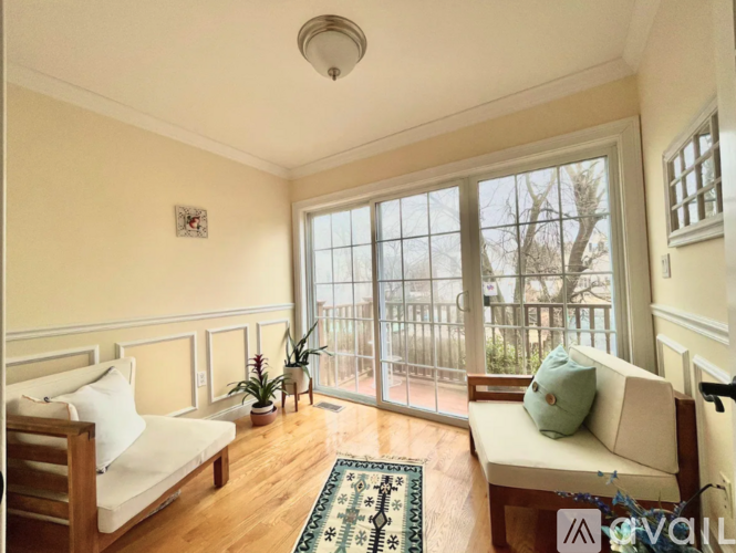 A living room with a white couch and a rug in front of a large window.