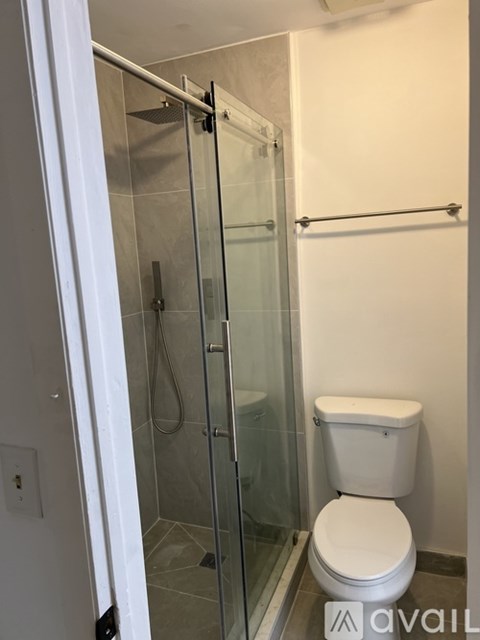 A white toilet sits next to a glass shower stall in a bathroom.
