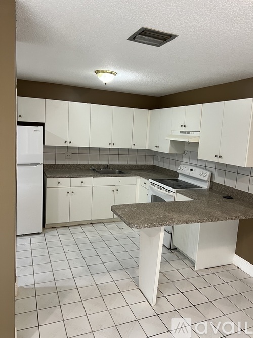 A kitchen with white cabinets and a granite counter.