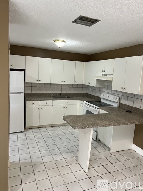 A kitchen with white cabinets and a granite counter.