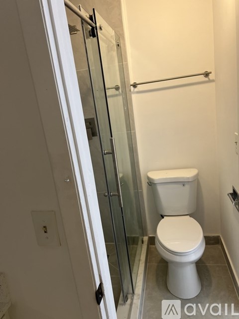 A white toilet in a small bathroom with a glass shower door.
