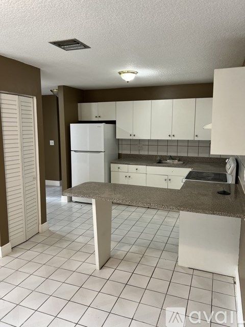A kitchen with white appliances and brown walls.