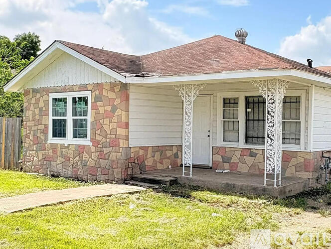 A small house with a porch and a brown roof.