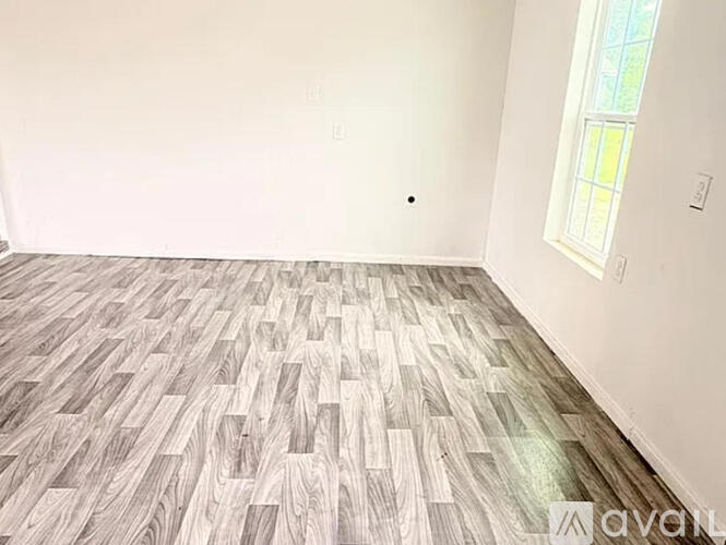 A room with wooden flooring and a window.