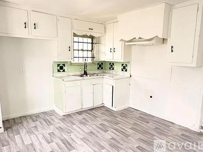A kitchen with white cabinets and a green backsplash.