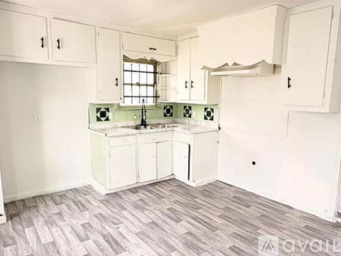 A kitchen with white cabinets and a green backsplash.