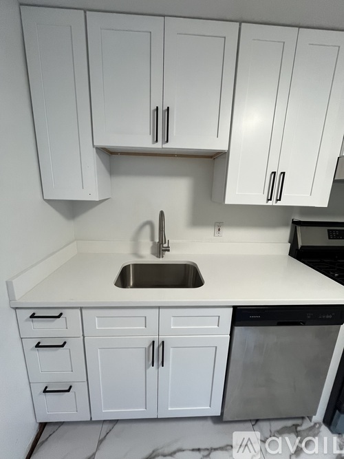 A kitchen with white cabinets and a marble countertop.