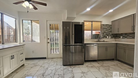 A kitchen with a marble floor and a stainless steel refrigerator.